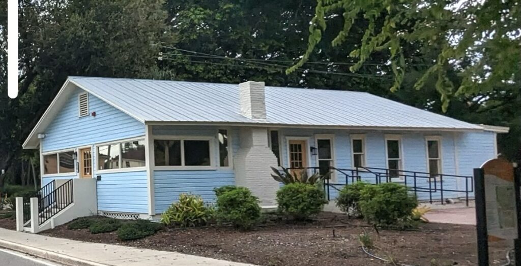 Side profile shot of a blue single-story home in the Newtown Sarasota, FL area known as The Historic Leonard Reid House